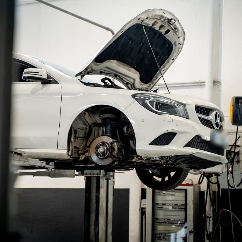 Una Mercedes-Benz bianca sul ponte, col cofano aperto e la ruota anteriore smontata