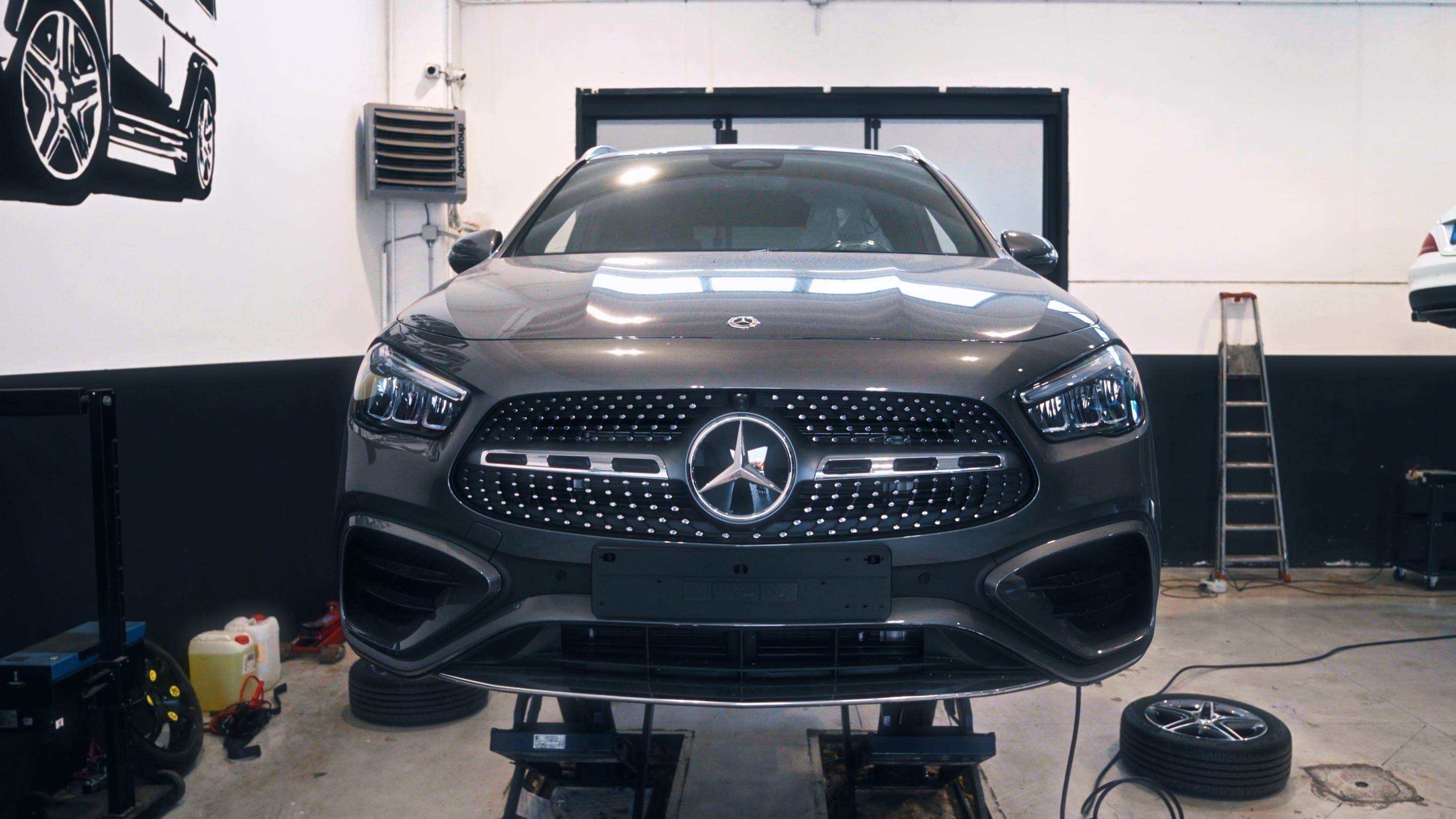 L’officina di Autolux a Vigevano: una Mercedes-Benz grigia sul ponte sollevatore, vista di fronte